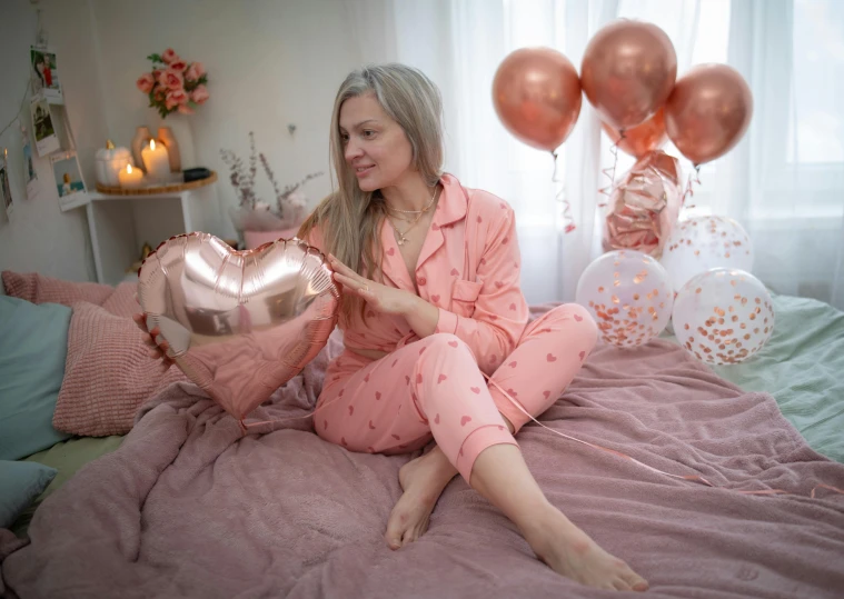 a lady sitting on her bed holding a heart shaped pillow