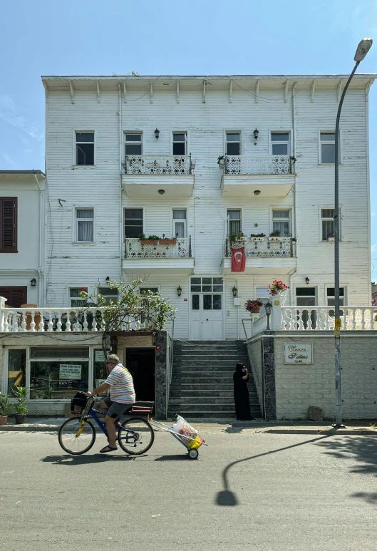 a woman on a bike rides past a white building