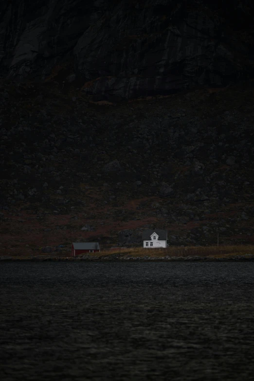 a dark and lonely boat sails by a small house