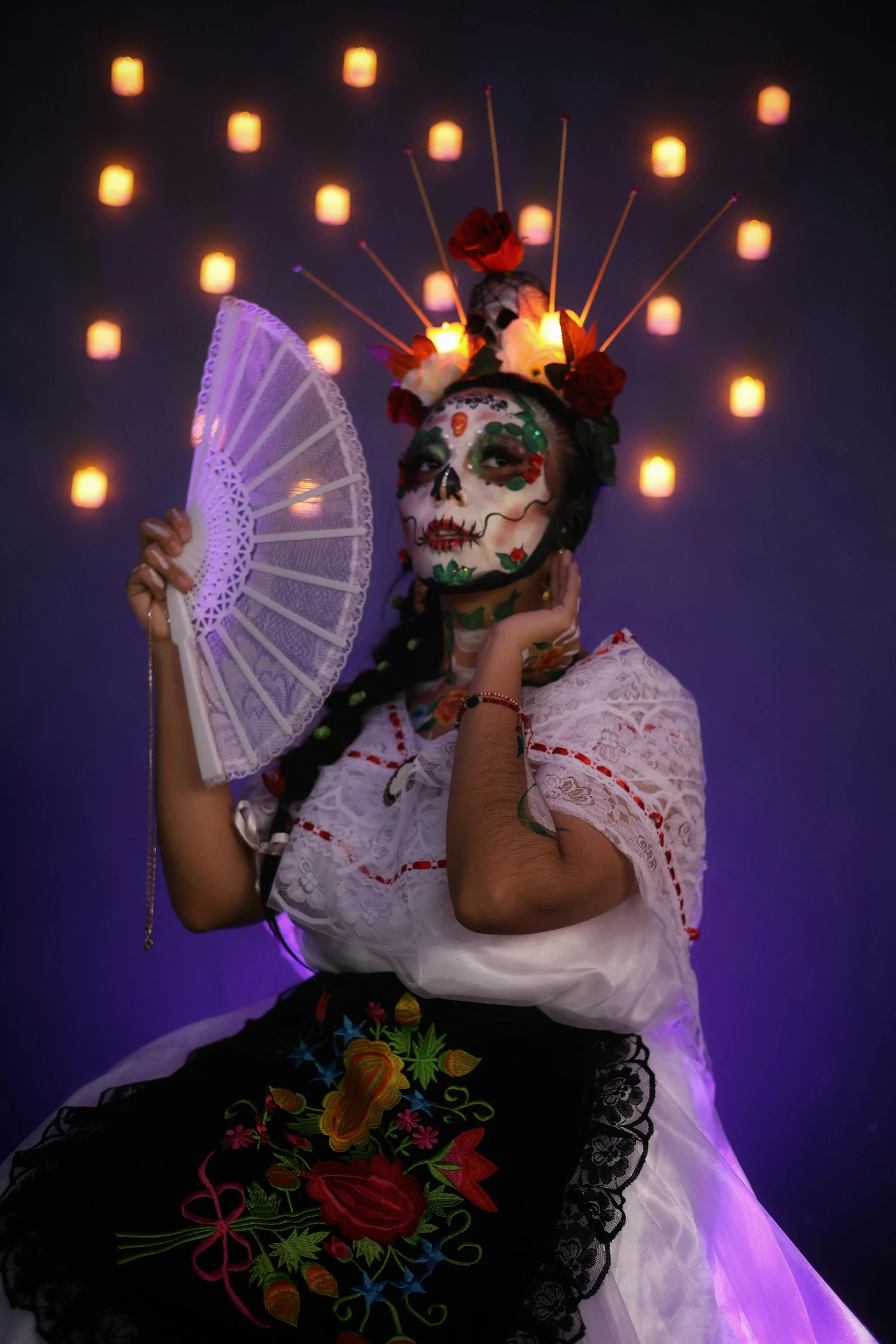 a woman with white and black makeup holds a fan