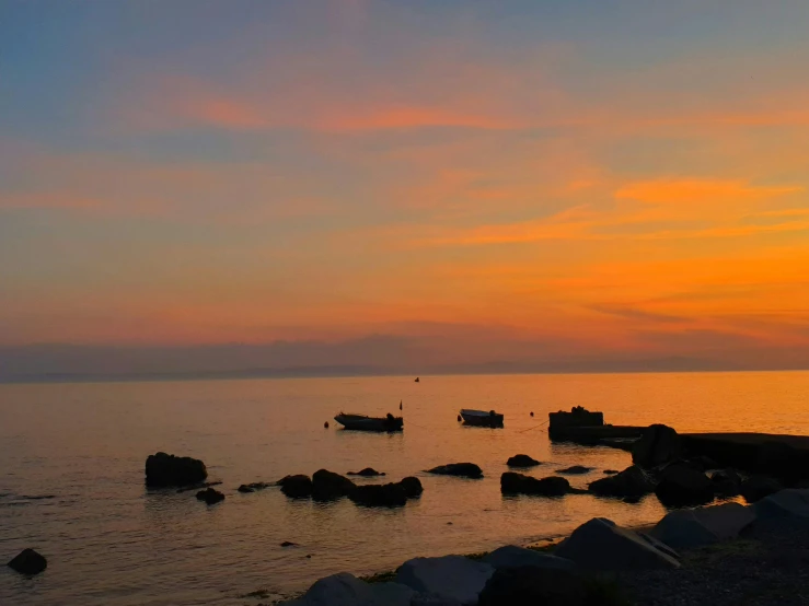 boats on the water at sunset with rocky shore