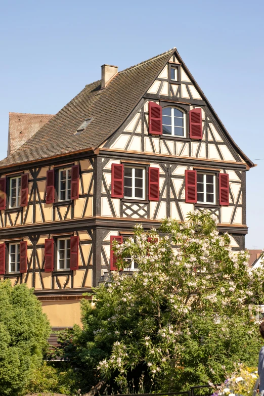 a tall brown building with red shutters on it's side