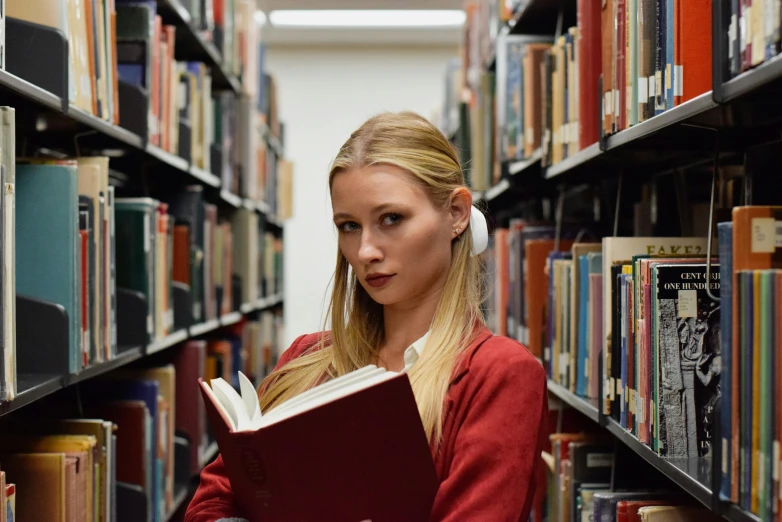 the blond woman is looking for a book in a liry