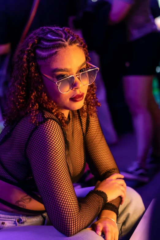 a girl with long curly hair and glasses sitting down