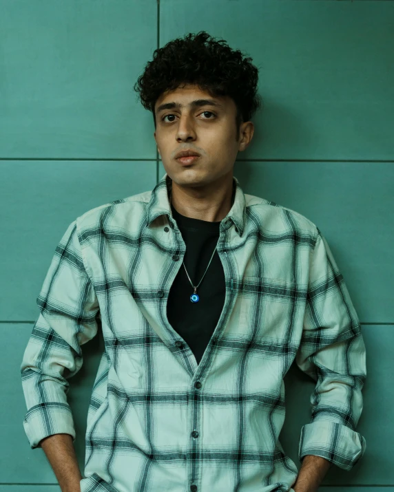 man leaning against the wall in front of a blue background