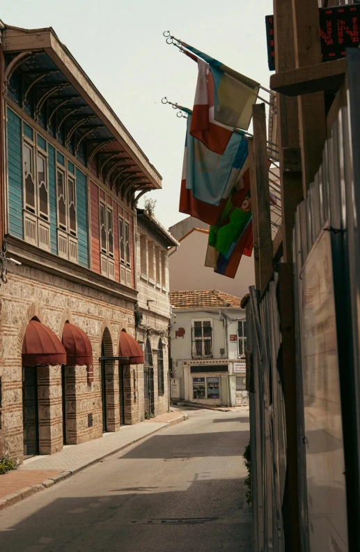 several colorful flags hang from a brick building