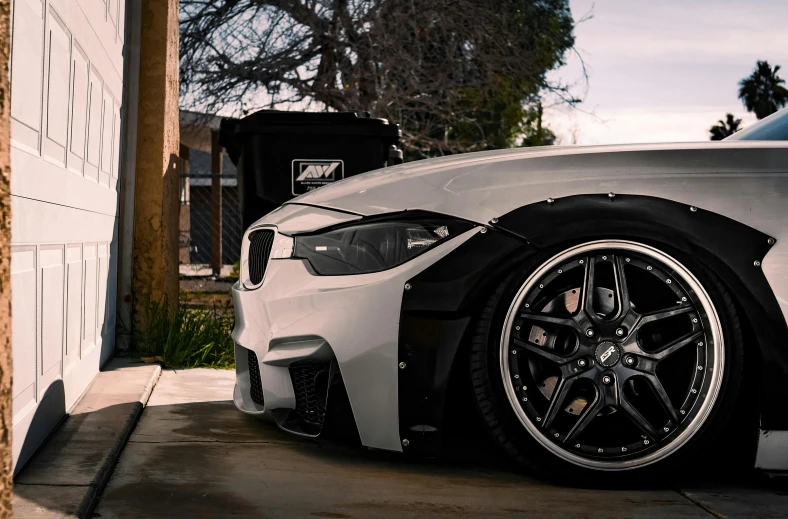 the front end of a white sports car parked next to a garage