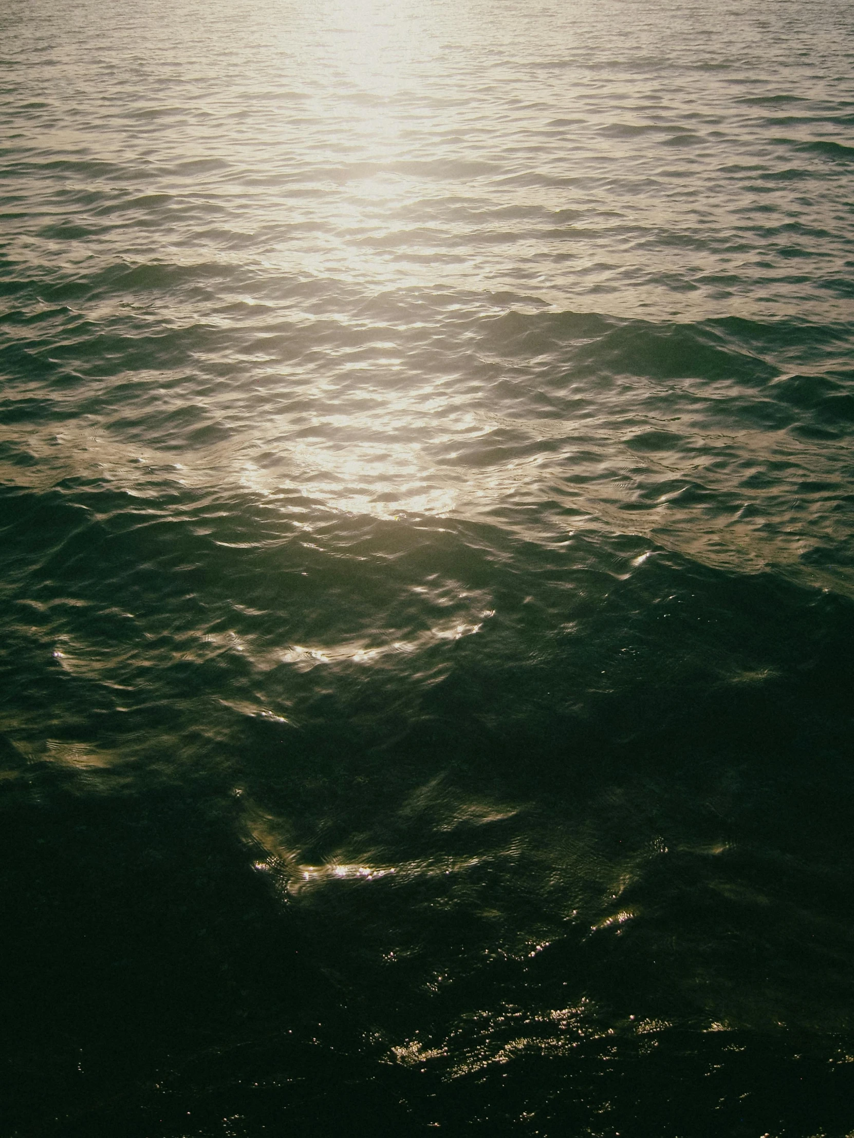 the sun shining through the water over a large body of water