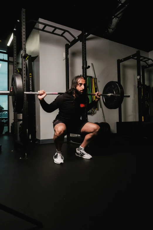 a person is squatting in the gym while holding a bar