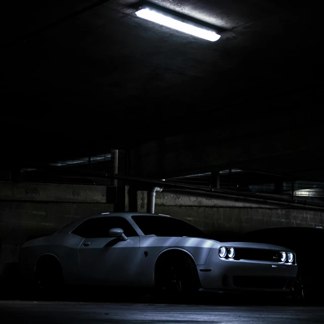 two white cars parked in a dark parking garage