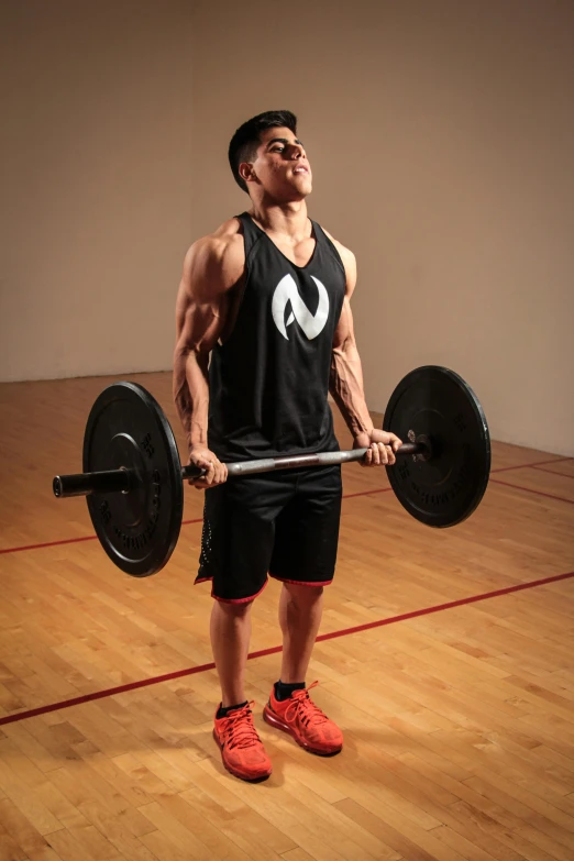 a man standing on top of a hard wood floor holding a barbell