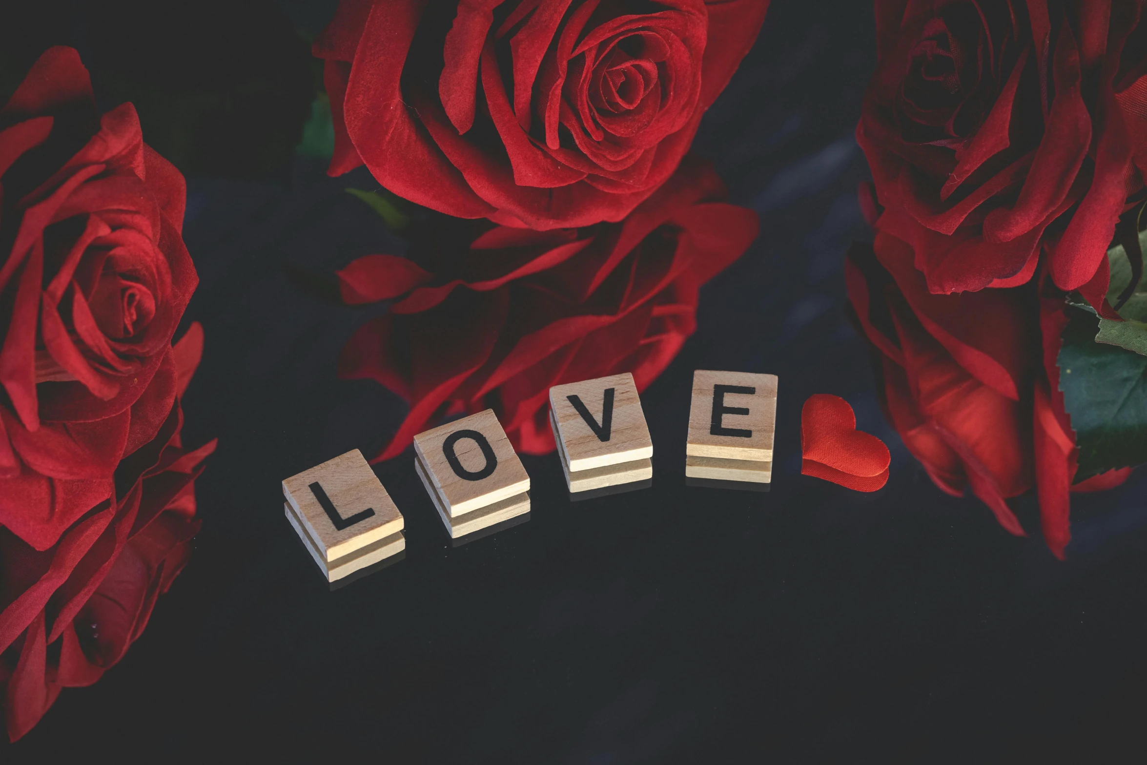 wooden block letters spell out love next to roses