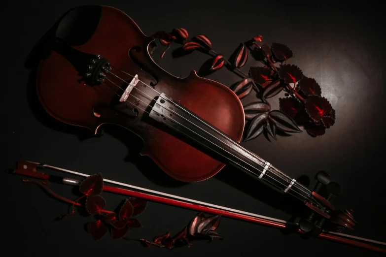 a violin lying near a flower arrangement on black background