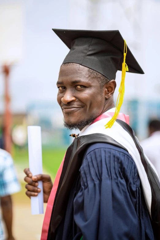 a person standing with a hat and gown and a diploma