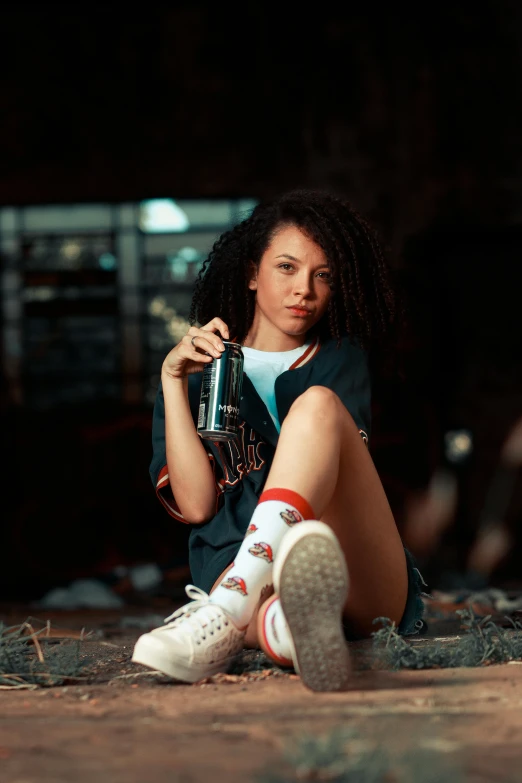 woman sitting on the ground drinking a drink