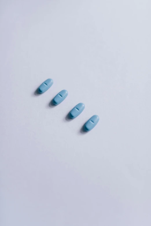 four blue pills are lined up against a white background