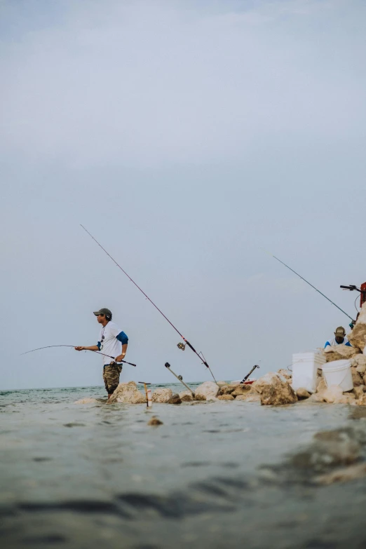 the young men are fishing on the rocky beach