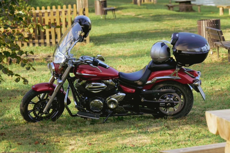 a red motorcycle parked in the grass next to a tree