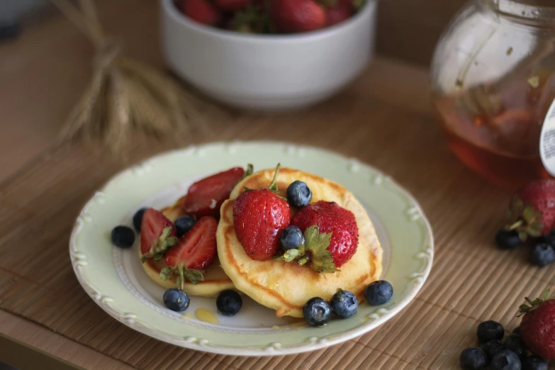 pancakes with strawberries, blueberries and syrup are served on a table