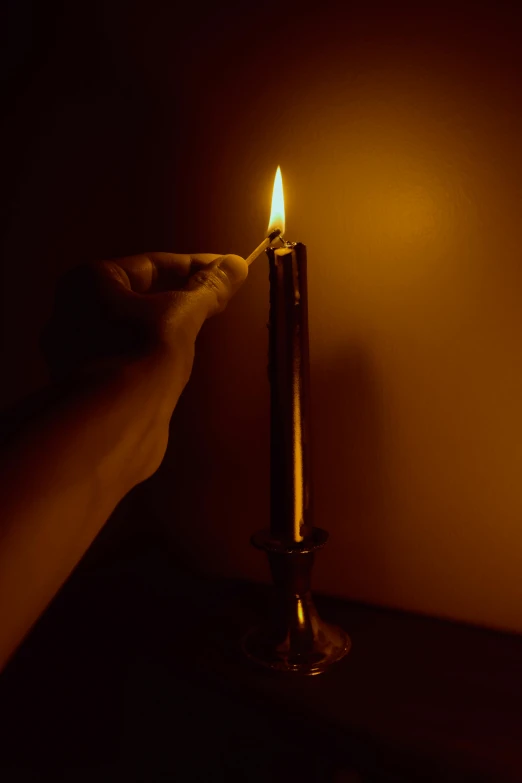 a hand holding the top of a candle lit up