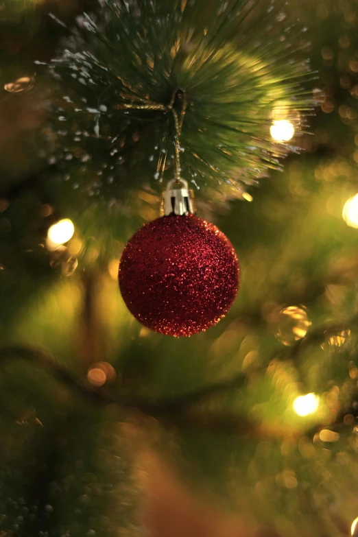 a red bauble ornament sitting on top of a christmas tree