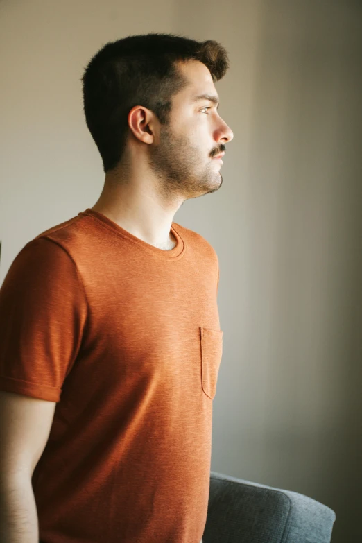 a man with his eyes closed standing next to a window