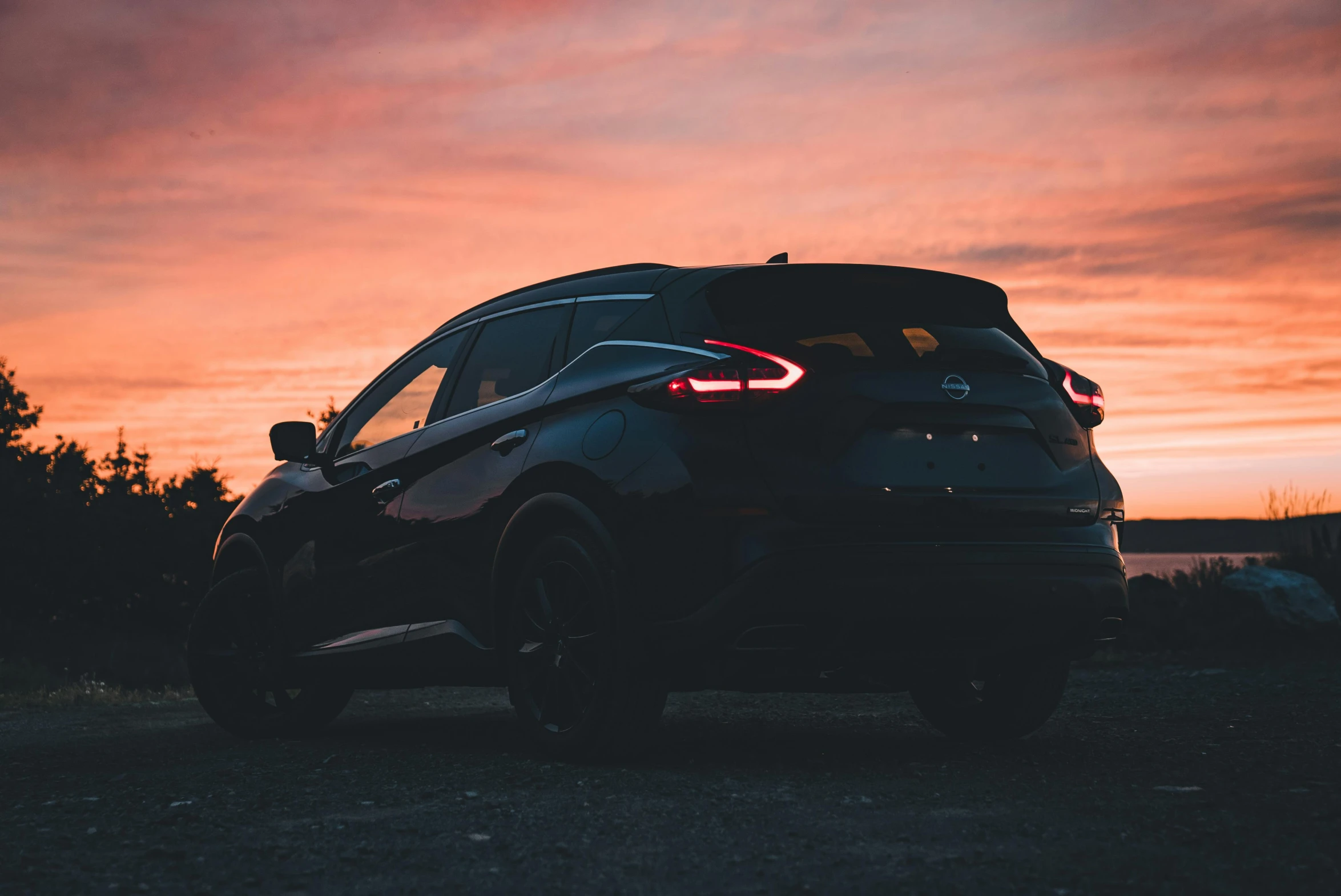 a car parked at the edge of the road in front of a sunset