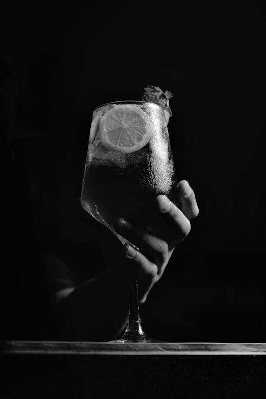 a person holds an ice drink with a lemon slice