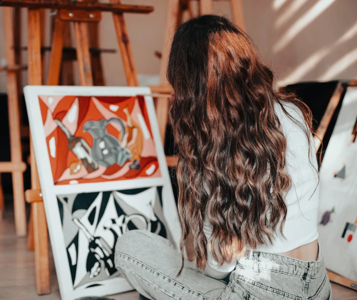 a woman sitting down next to a piece of art