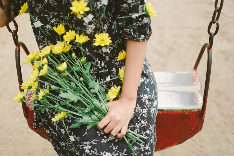 a girl on a swing with a bouquet of flowers