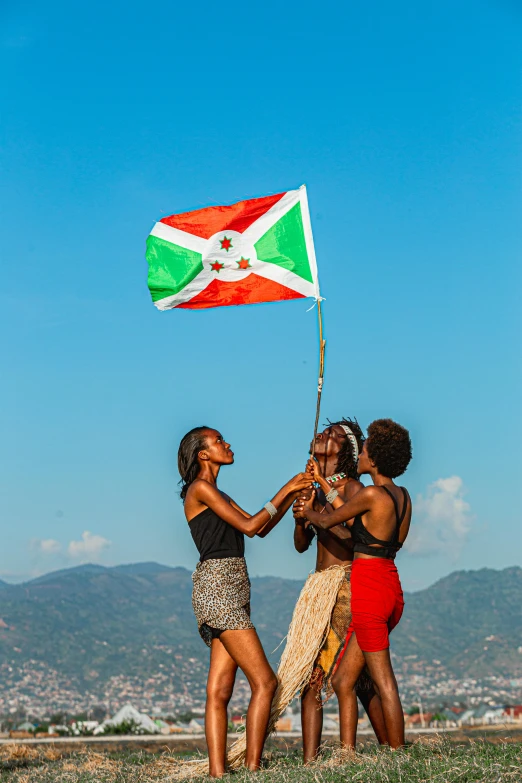 three woman are holding a flag together while standing together