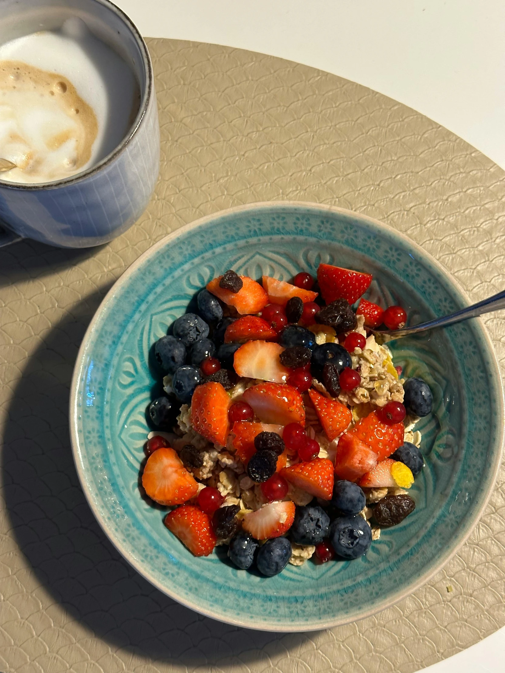 a bowl of cereal, berries and milk with a beverage