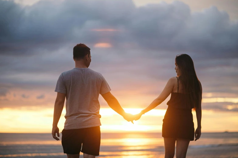 two people holding hands as the sun goes down