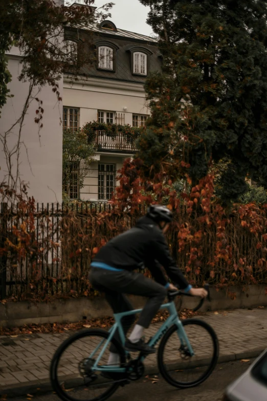 a man in black jacket riding a blue bike down the street