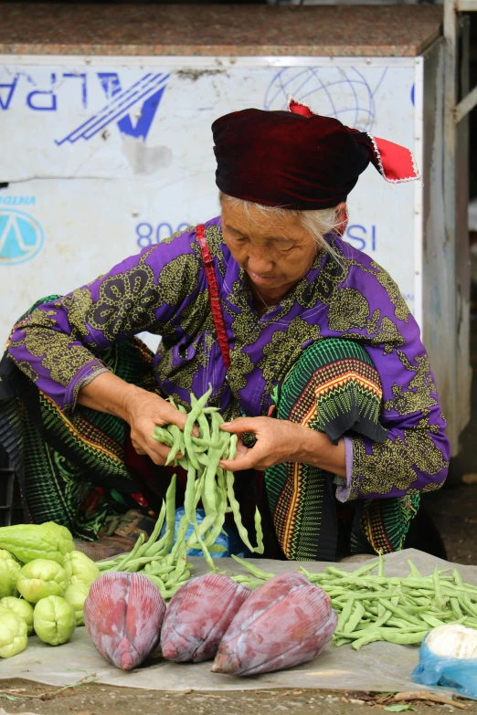 a woman kneeling next to a table full of vegetables