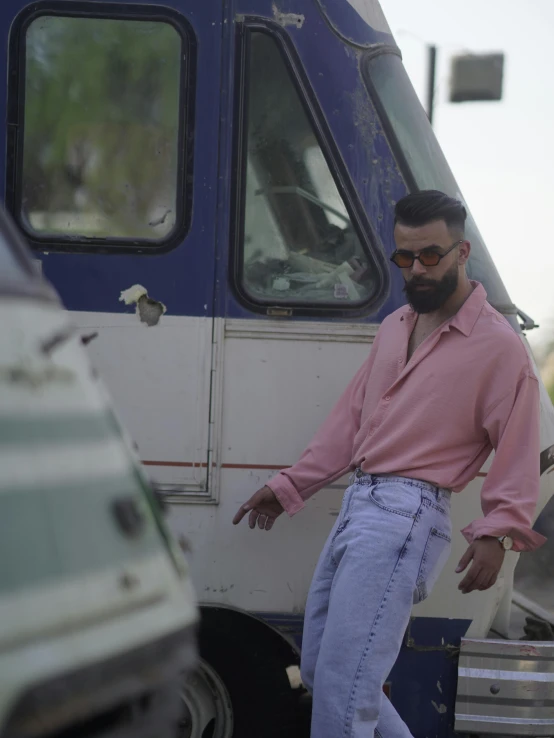 a man with a beard in front of a parked car