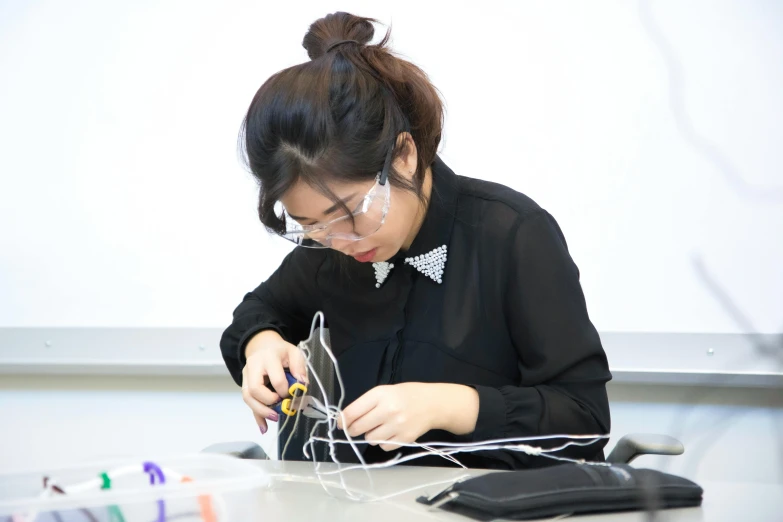 a woman making a necklace with string and a pair of scissors