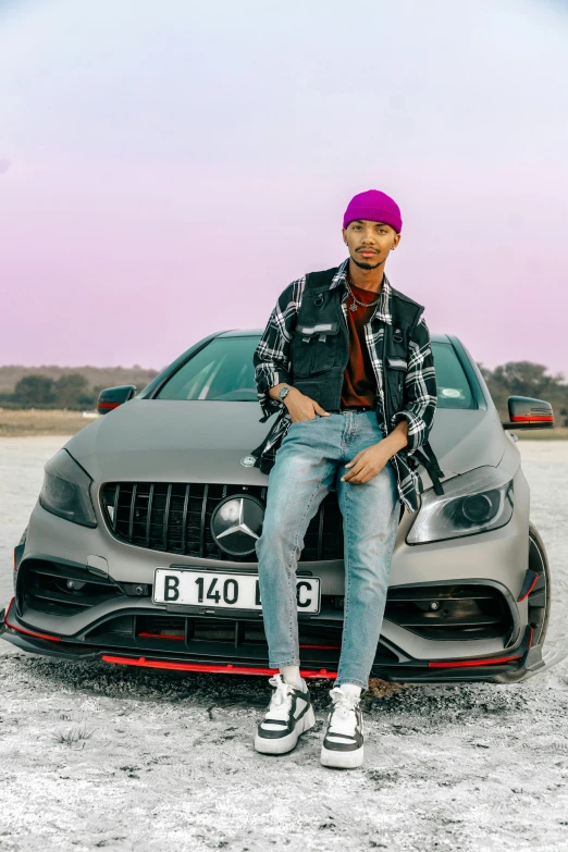 the man is sitting on the hood of a mercedes