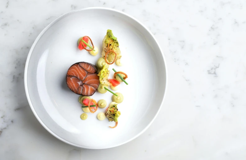 a white plate topped with a cut up fish and a lot of food