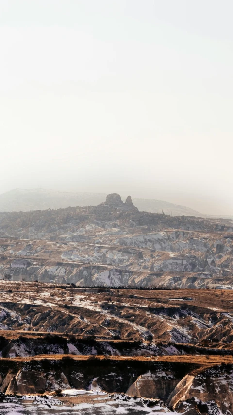 a sheep grazes along the edge of a barren valley