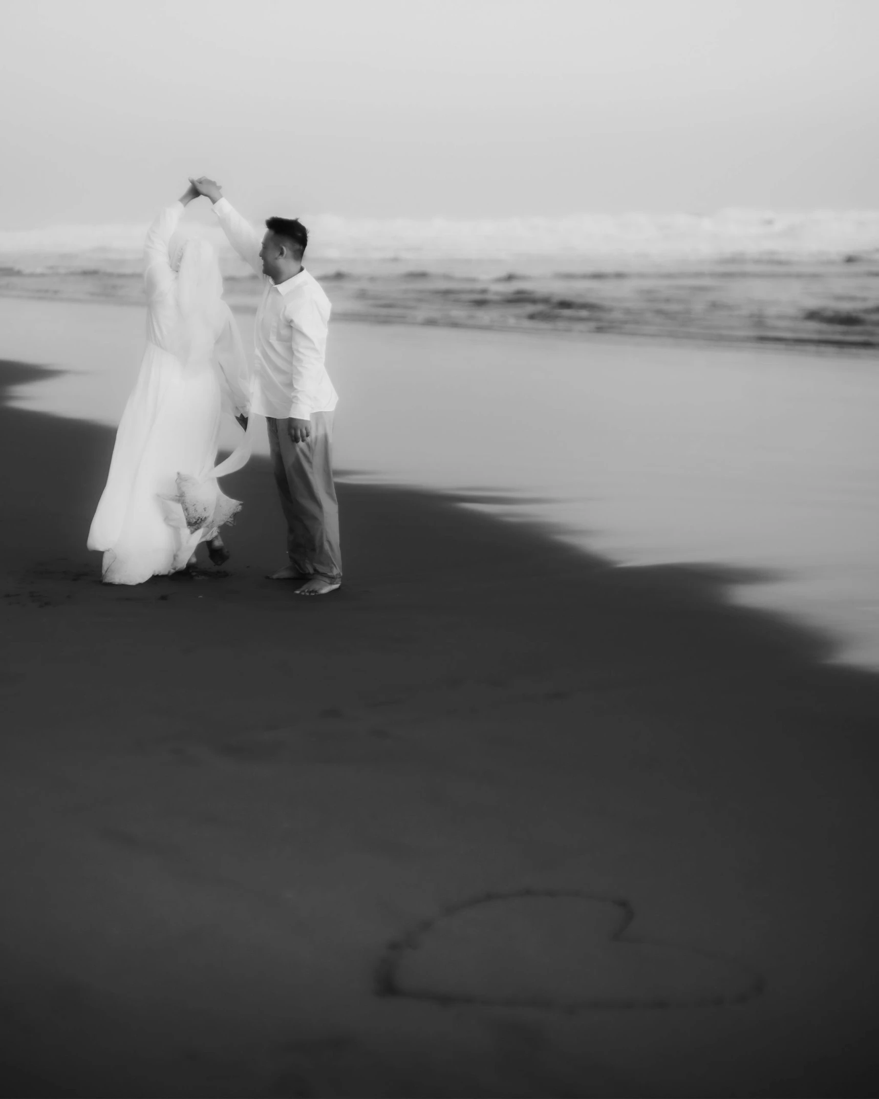 a bride and groom walk together on a beach