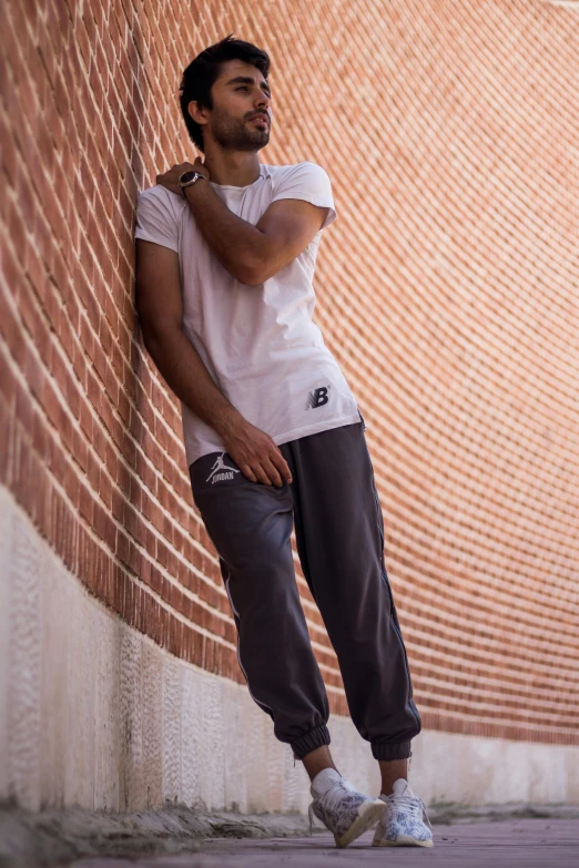 a man leaning against a wall holding onto his hand