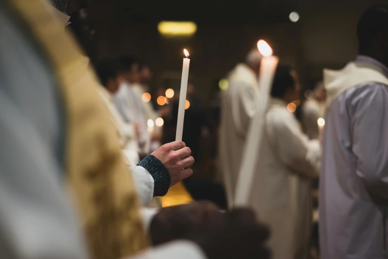 people with robes, holding up lit candles