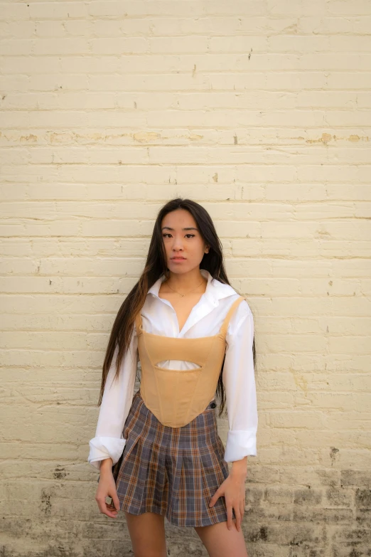 a young woman posing in front of a brick wall