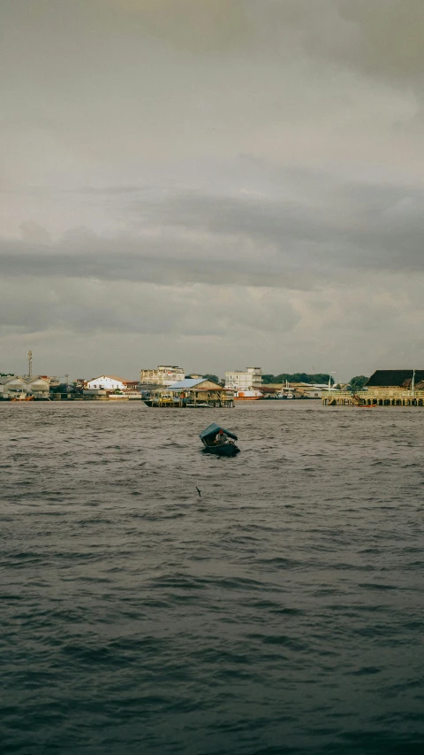 boats in the water near city buildings on a cloudy day