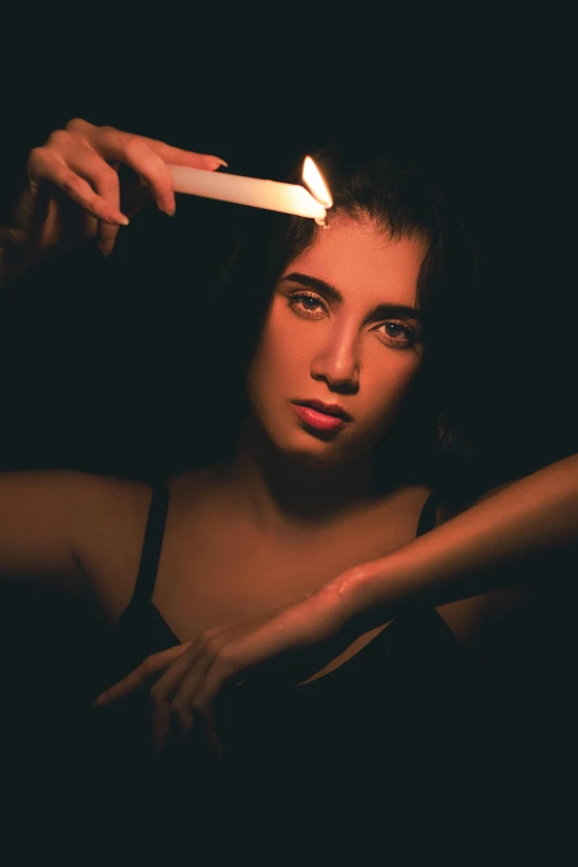 a woman holding a lit candle at night