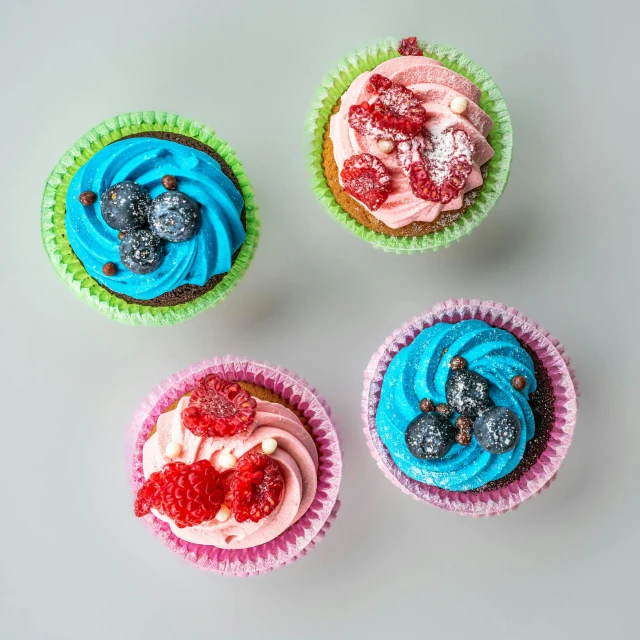 cupcakes with different colored icing and fresh berries