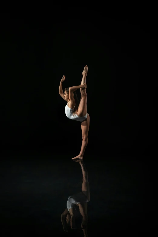 a woman is dancing in the dark, doing a splitstand