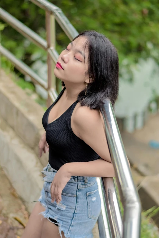 a woman leaning on a metal handrail near trees