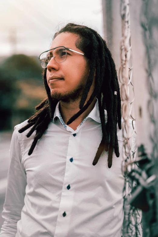 a man wearing glasses with dreadlocks posing